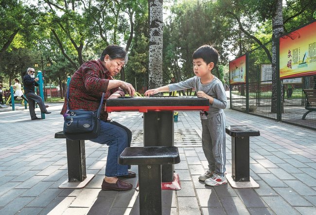 Një e moshuar luajti shahun kinez me nipin e saj në një park në Pekin në Maj të vjetshëm/ Photo nga KEVIN FRAYER për "CHINA DAILY"