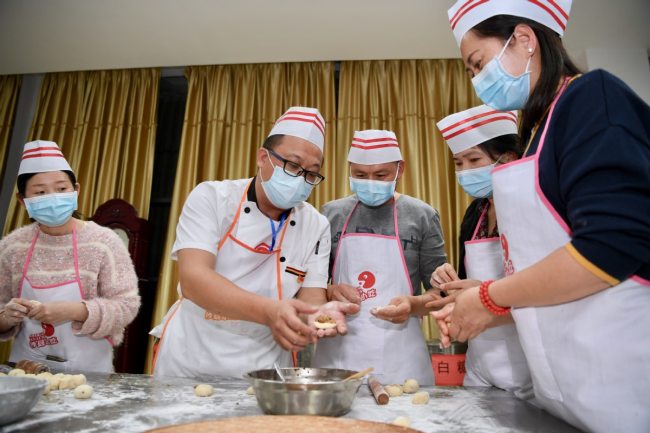 Një profesionist u mëson studentëve të gatuajnë në një qendër përgatijeje në kontenë Shaxian./ Xinhua