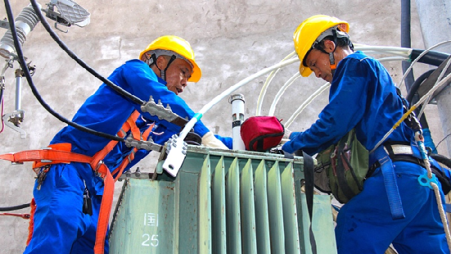 Punëtorët e Rrjetit Elektrik Shtetëror duke kontrolluar e rregulluar kabllot në kontenë Tongjiang të provincës Sichuan të Kinës Jugperëndimore, 21 gusht 2022/ CFP
