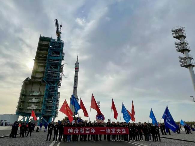 Zaměstnanci Centra pro vypouštění satelitů Jiuquan v severozápadní Číně se 7. října 2021 shromažďovali k fotografování, jak se raketa Dlouhý pochod 2F Y13 přesouvala na odpalovací plochu. / CMSA