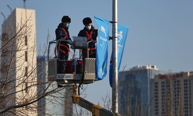 Pracovníci mění pouliční plakáty s paralympijským logem, v Pekingu, dne 24. února 2022. Fotografie: CFP