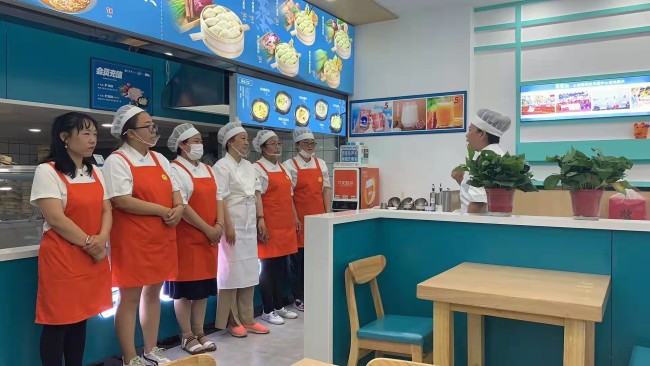 Snímek: Wang Chunzhi (vpravo) mluví se svými kolegy ve své knedlíkové restauraci v Changchunu v severovýchodní čínské provincii Jilin; 30. června 2021. / Wang Chunzhi