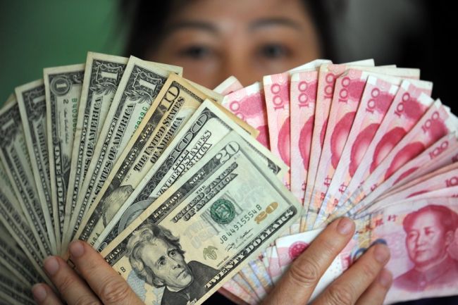 Ilustrační fotka ukazuje bankovky čínské měny RMB a US dolary v Qinghai, v jihočínské provincii Hanan.