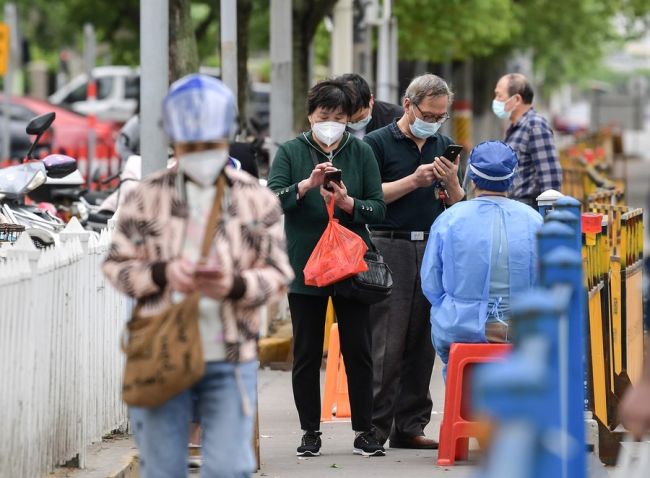 Snímek: Obyvatelé ukazují své zprávy o testech nukleových kyselin před vstupem na trh v okrese Jiading (Ťia-ting) ve východočínské Šanghaji; 9. května 2022. / Xinhua