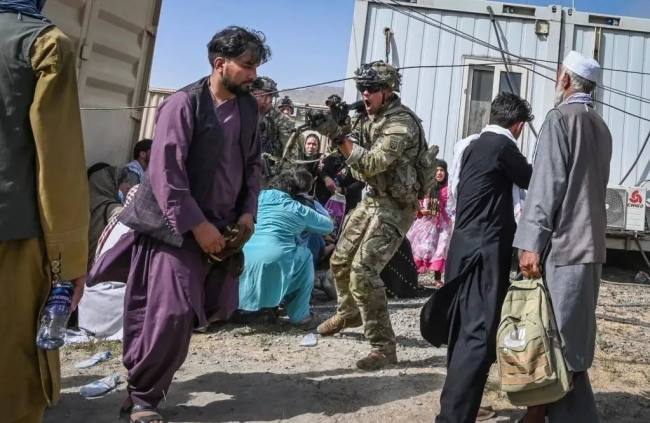 Usona soldato direktis sian pafilon al afganoj, kiuj provas retiriĝi, en la afgana kabula flughaveno la 16-an de aŭgusto, 2021.