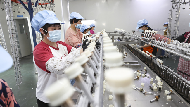 Laborantoj produktas botelajn ĉapojn en fabriko en Lianyungang, Jiangsu-provinco, Ĉinio, la 26-an de aŭgusto, 2022./CFP