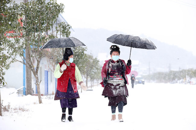 Des gens marchent sous la neige, le 22 février, au xian de Danzhai, à la préfecture autonome Miao et Dong de Qiandongnan, dans la province du Guizhou (sud-ouest).