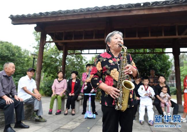 Ying Miaofang spielt Saxophon in einem Park.