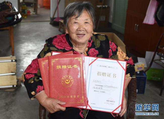 Ying Miaofang zeigt ihre Urkunden für ihre warmherzigen Spenden.