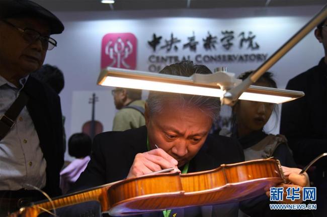 Gao Tongtong, Lehrer aus dem Forschungsinstitut für Geigenherstellung der Zentralen Musikakademie Chinas, restauriert vor Ort eine beschädigte Geige.