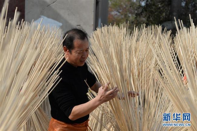 Wang Yansong stellt die Rippen für Wachstuchschirme im Guomin Werk her. 