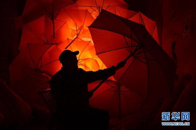 Handwerker Wang Yansong überprüft neue Wachstuchschirme im Guomin Wachstuchregenschirmwerk.