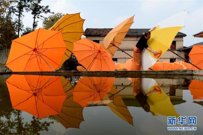 Zheng Guomin bürstet Tungöl auf einen Regenschirm, 7. November 2019.