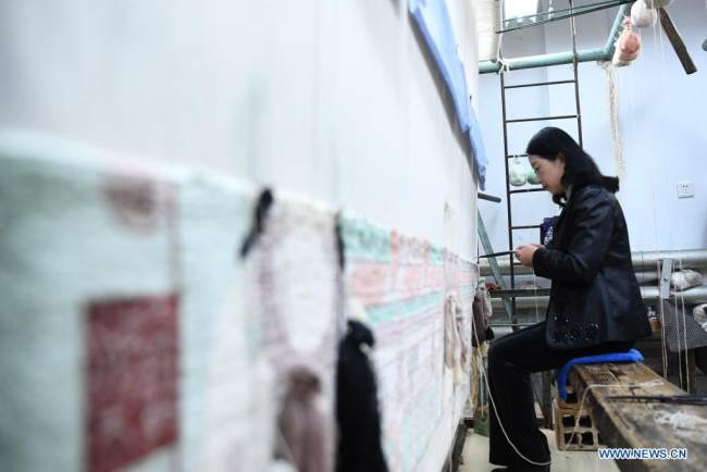 Η Χουάνγκ Τζινγκρόνγκ υφαίνει ένα μεταξωτό χαλί σε ένα εργαστήριο ύφανσης της Xintian Silk Carpet Company στην πόλη Τιενσούι της επαρχίας Γκανσού στην βορειοδυτική Κίνα, στις 12 Απριλίου 2021. 