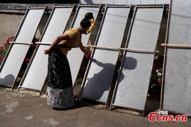 Η Γιου Καν’εν, μια κληρονόμος των δεξιοτήτων κατασκευής χαρτιού της εθνότητας των Ντάι, ελέγχει το χαρτί που αποξηραίνει σε καλούπια, στην κομητεία Μενγκχάι στον αυτόνομο νομό Ντάι της περιοχής Σισουανγκμπανά στην επαρχία Γιουνάν της νοτιοδυτικής Κίνας, την 1η Σεπτεμβρίου 2021. (Φωτογραφία: China News Service/Kang Ping)