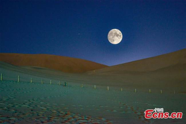Ένα κρεμαστό «σούπερ φεγγάρι» πάνω από την τεράστια έρημο στο Ντουνχουάνγκ, στην επαρχία Γκανσού της βορειοδυτικής Κίνας, 21 Σεπτεμβρίου 2021. (Φωτογραφία: China News Service/Wang Binyin)