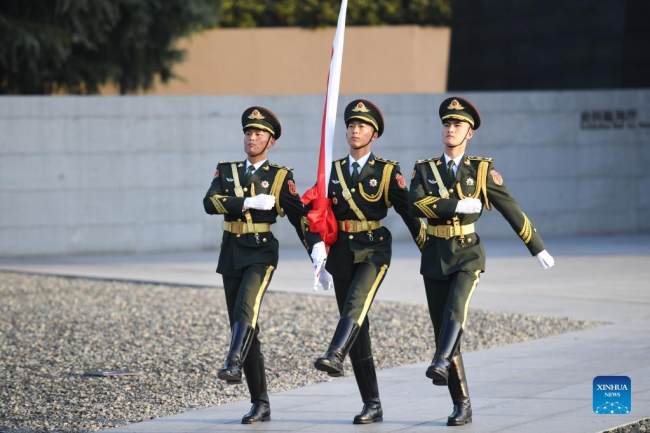 Η τιμητική φρουρά συνοδεύει την εθνική σημαία πριν από την εθνική τελετή μνήμης για τα θύματα της σφαγής της Ναντζίνγκ στην πόλη Ναντζίνγκ, πρωτεύουσα της επαρχίας Τζιανγκσού της ανατολικής Κίνας, 13 Δεκεμβρίου 2021. (φωτογραφία/Xinhua)
