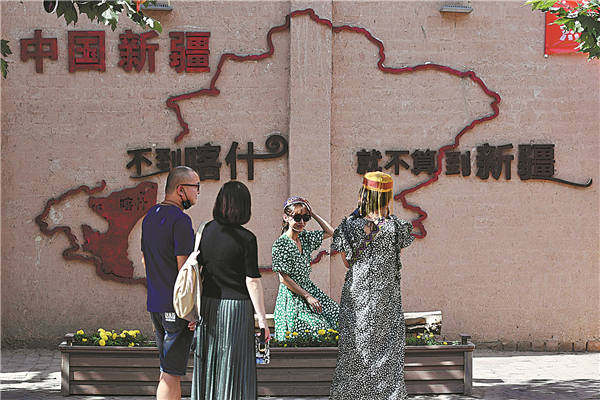 Επισκέπτες τραβάνε φωτογραφίες μπροστά από έναν χάρτη του Σιντζιάνγκ, ο οποίος περιλαμβάνει επίσης το ρητό: "Δεν έχετε πάει στο Σιντζιάνγκ αν δεν έχετε πάει στο Κασγκάρ..." [Φωτογραφία/China Daily]