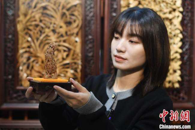 Η Τσεν Τζια παρουσιάζει ένα έργο ξυλογλυπτικής μινιατούρα. (Chinanews.com/Chen Chuhong)
