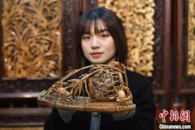 Η Τσεν Τζια παρουσιάζει ένα έργο της τέχνης της ξυλογλυπτικής Τσαοτζόου. (Chinanews.com/Chen Chuhong)