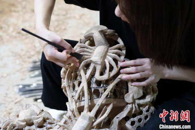 Η Τσεν Τζια δημιουργεί ένα έργο ξυλογλυπτικής Τσαοτζόου. (Chinanews.com/Chen Chuhong)