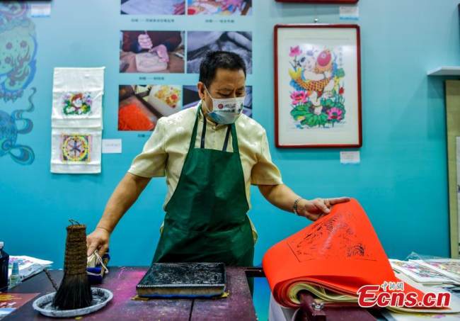 Κληρονόμος παραδοσιακής τέχνης δημιουργεί πρωτοχρονιάτικη ζωγραφική σε ξυλό Γουτσιάνγκ κατά τη διάρκεια μιας έκθεσης άυλης πολιτιστικής κληρονομιάς στο Μουσείο Τέχνης Σιντζιάνγκ, στην πρωτεύουσα Ουρούμτσι της αυτόνομης περιοχής Σιντζιάνγκ Ουιγκούρ της βορειοδυτικής Κίνας, 31 Ιουλίου 2022. 