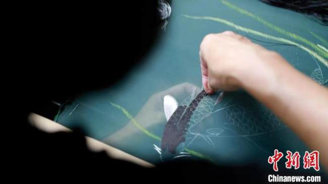 Η Μενγκ Ντετζί ενώ εργάζεται σε ένα κομμάτι κεντήματος Σου με μια εικόνα ενός φανταχτερού κυπρίνου. (Φωτογραφία/Tang Qihao)