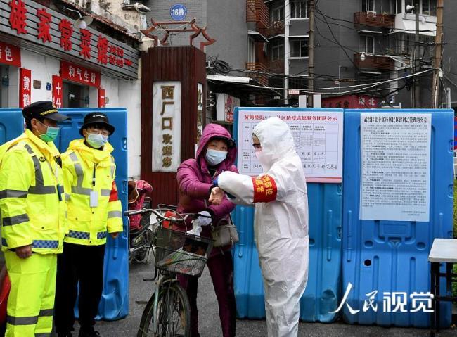 Un angajat din Wuhan ia temperatura unui locuitor la intrarea în cartier.
