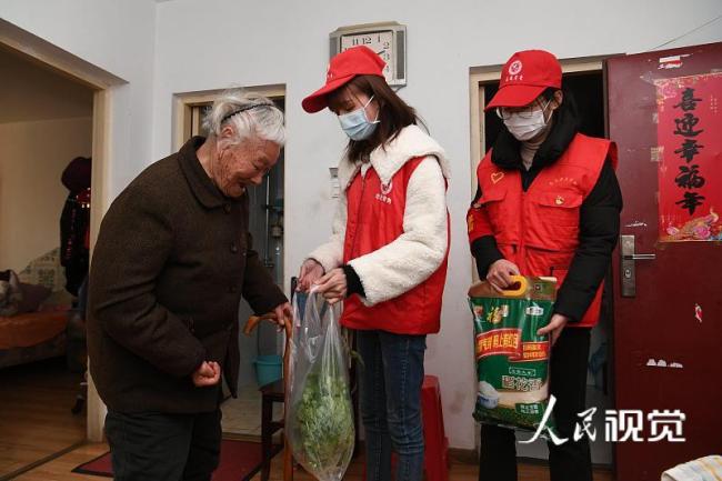 Studenții voluntari din orașul Hefei livrează pachete cu mâncare unei femei vârstnice în timpul pandemiei.