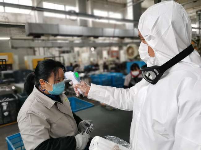 O angajată își ia temperatura în hală în timpul pandemiei
