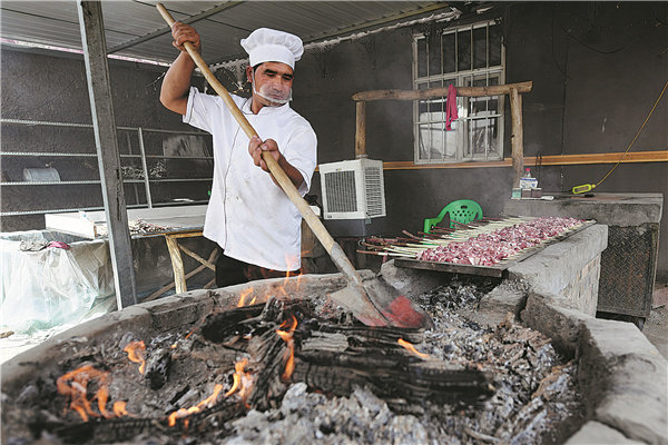 Šéfkuchař griluje ve vesnici Shaya (Ša-ja) v Ujgurské autonomní oblasti Xinjiang. [Fotografie: Wei Xiaohao / deník China Daily]