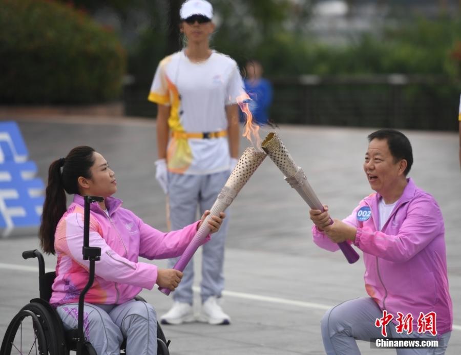 Οι φορείς της δάδας, Ταν Γιουτζιάο (αριστερά) δίνει τη φλόγα στον Λέι Μινγκ κατά τη διάρκεια της λαμπαδηδρομίας των 4ων Ασιατικών Αγώνων Para Games στην κομητεία Τσουν’αν, Χανγκτζόου, στην επαρχία Τζετζιάνγκ της ανατολικής Κίνας, 19 Οκτωβρίου 2023 (Φωτογραφία: China News Service/Wang Gang)