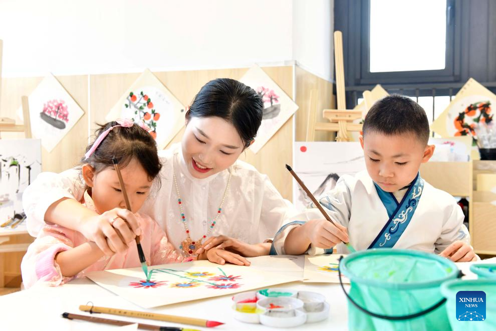Η δασκάλα Χου Γουενγιά διδάσκει στα παιδιά να ζωγραφίζουν στο στυλ της παραδοσιακής κινεζικής ζωγραφικής στο νηπιαγωγείο Σανγουάνγκ στο Τζινάν, στην επαρχία Σανντόνγκ της ανατολικής Κίνας, στις 29 Νοεμβρίου 2023. (Xinhua/Guo Xulei)