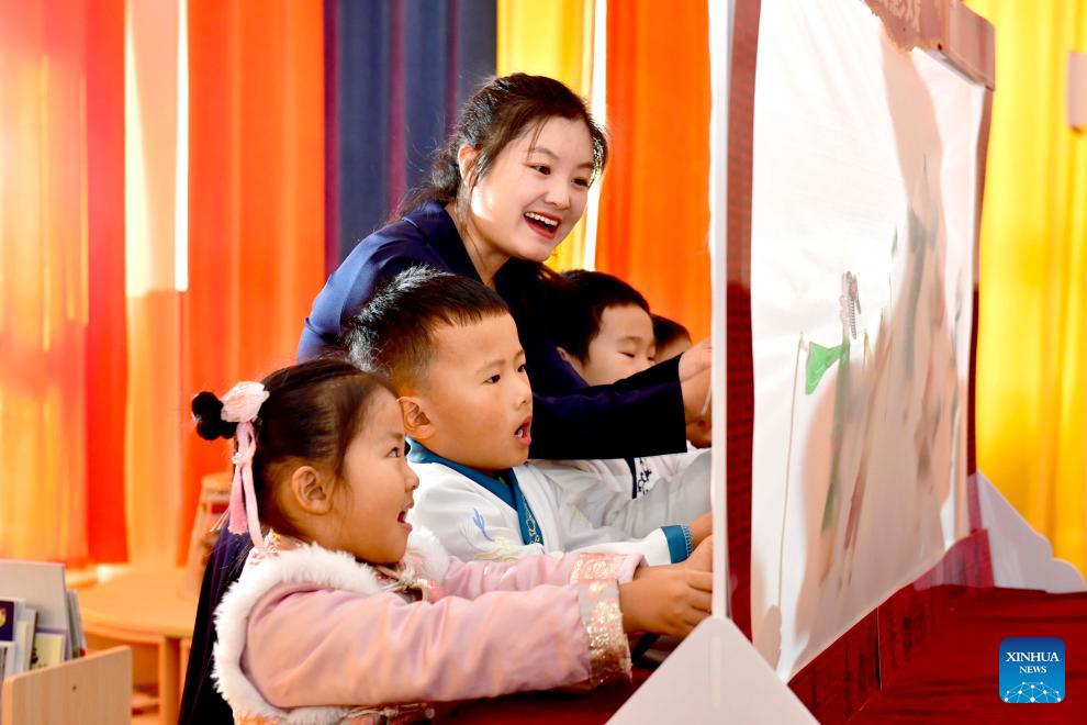 Η δασκάλα Τζου Τσινγκμίν διδάσκει στα παιδιά να παίζουν με τις σκιές στο νηπιαγωγείο Σανγουάνγκ στο Τζινάν, στην επαρχία Σανντόνγκ της ανατολικής Κίνας, στις 29 Νοεμβρίου 2023. (Xinhua/Guo Xulei)
