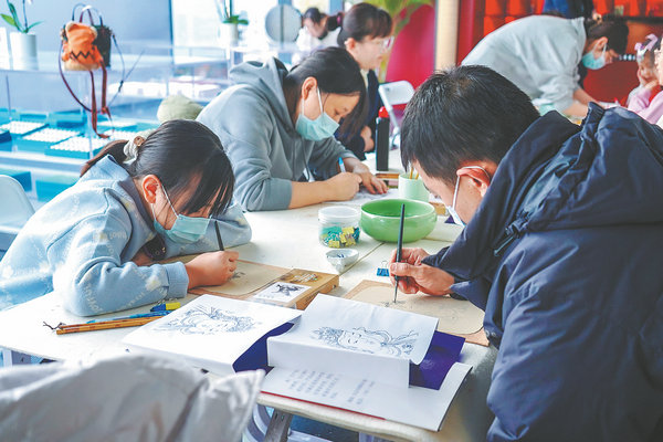 Οι επισκέπτες δοκιμάζουν να φτιάξουν τοιχογραφίες με παραδοσιακές μεθόδους στο Κέντρο Τέχνης του Ναού Φαχάι τον Δεκέμβριο του 2023. [Φωτογραφία από την China Daily]