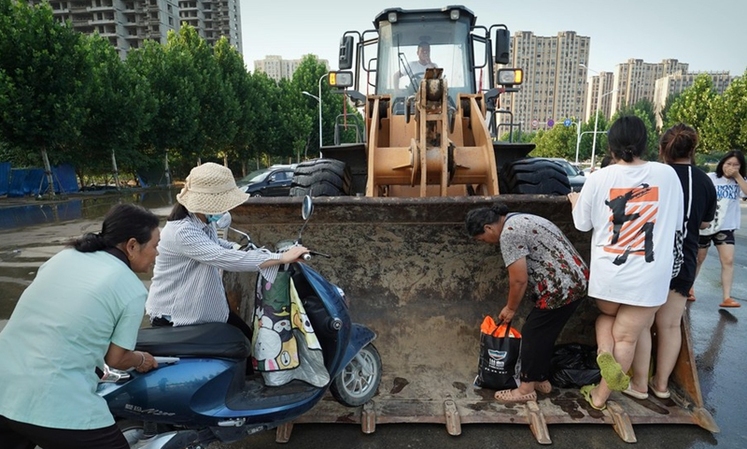 راننده این بیل‌مکانیکی به ساکنان در مناطق سیل زده در هه‌نان، مرکز چین کمک می کند_fororder_2-4