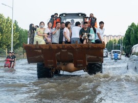 راننده این بیل‌مکانیکی به ساکنان در مناطق سیل زده در هه‌نان، مرکز چین کمک می کندا